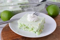 a white plate topped with a piece of cake next to a bowl of limes