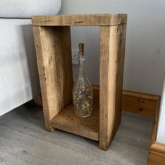 a small wooden box with a bottle in it on the floor next to a bed