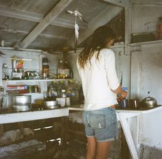 a woman standing at the sink in a dirty kitchen