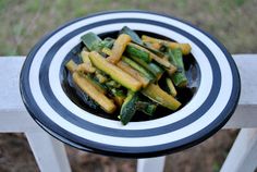 a bowl filled with vegetables sitting on top of a white and black tablecloth next to grass