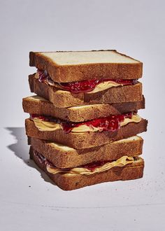 three sandwiches stacked on top of each other with jelly and peanut butter spread on them