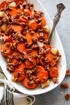 a white bowl filled with carrots and pecans on top of a gray table