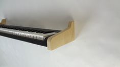 a wooden shelf with an electronic keyboard on it's back end, against a white wall