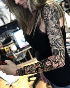 a woman with a tattoo on her arm holding a cell phone