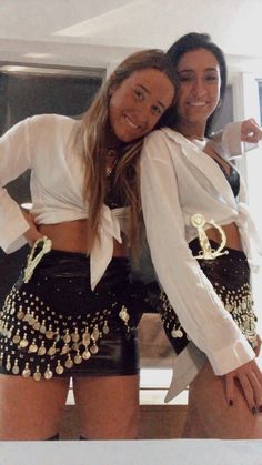 two women in short shorts and white shirts posing for the camera with their arms around each other