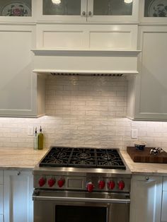 a stove top oven sitting inside of a kitchen next to white cabinets and counter tops