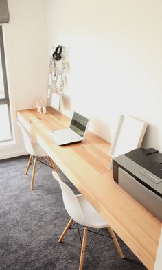 a desk with a printer and laptop on it in front of a large window that looks out onto the street