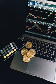 a laptop computer sitting on top of a desk next to coins and a calculator