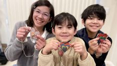 two children and an adult are holding up their cell phones