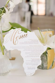 a menu card is sitting on a table with flowers in vases and other items