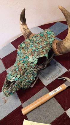 an animal's skull is covered with mosaic tiles and has a hammer in it