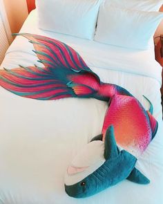 a large stuffed fish laying on top of a bed