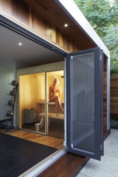 a woman is sitting in an outdoor saunace with sliding doors on the side