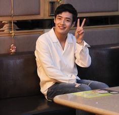 a man sitting at a table making the peace sign with his hand in front of him