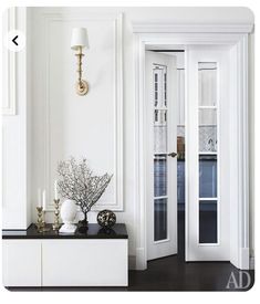 an entryway with white walls and black countertop, two vases filled with flowers