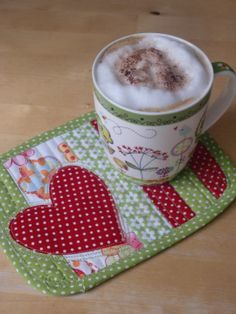 a coffee cup on a place mat with a heart design in the middle and a mug filled with foam