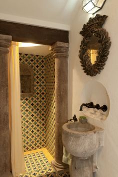 a bathroom with yellow and black tiles on the walls, a pedestal sink and mirror