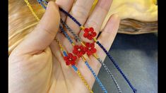 a woman holding three red flowers in her hand with beads on the ring and beaded bracelets