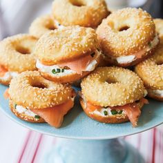 bagels with cream cheese and salmon on them are arranged on a blue platter