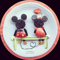 two mickey mouses sitting on top of a white plate with red and black decorations