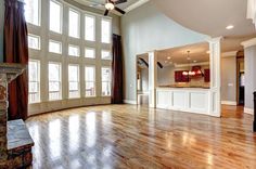 an empty living room with wood floors and large windows