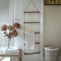 a towel rack hanging on the wall next to a basket with dried flowers in it