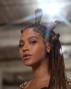 a woman with long braids standing in front of a light shining on her face