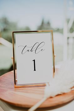 a table number is placed on top of a wooden plate with white feathers around it