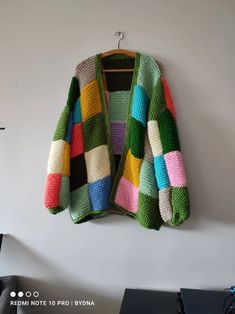 a multicolored sweater hanging up on a wall next to a computer keyboard and mouse