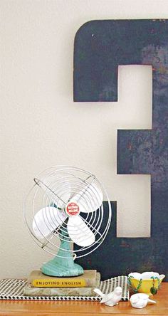 the letter e is made out of wood and has a fan on top of it