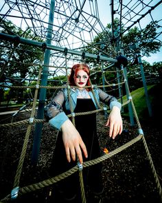 a woman with red hair standing on top of a rope structure