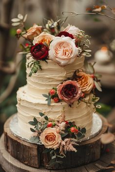 a wedding cake with flowers on it sitting on top of a tree stump in the woods