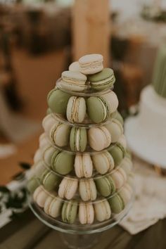 a stack of macaroons sitting on top of a glass cake plate next to a wedding cake