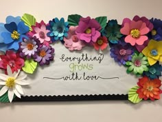 colorful paper flowers are arranged on a white board with the words everything grows with love