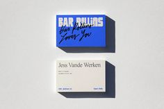 two business cards sitting next to each other on top of a white surface with blue writing