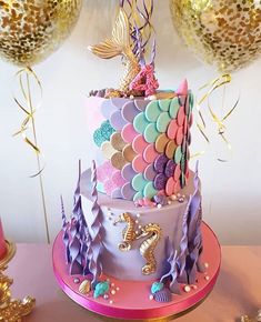 a three tiered cake with mermaid decorations on the top and under it's icing