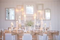 the table is set with white candles and flowers in vases on top of them