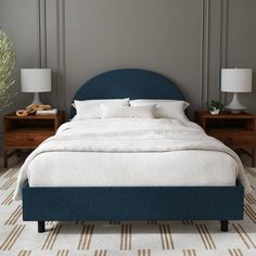 a bed with two nightstands and a blue headboard on top of the bed