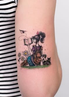 a woman with a book and cat tattoo on her arm