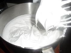 a metal bowl filled with white liquid on top of a wooden table