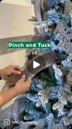 a person is decorating a christmas tree with silver and green decorations on it's branches