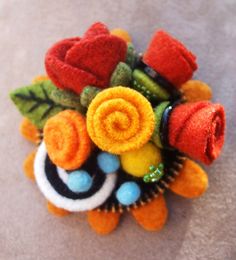 a close up of a flower brooch with felt flowers on it's center