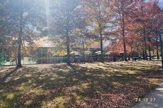 the tennis court is surrounded by trees and leaves on the grass in front of it