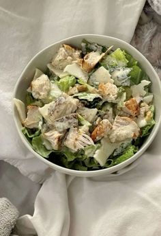 a white bowl filled with salad sitting on top of a bed next to a teddy bear