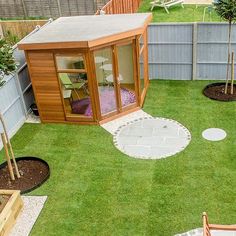 a small backyard with green grass and wooden fenced in area, including a garden shed