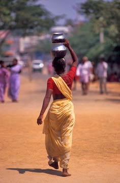 a woman carrying a bucket on her head