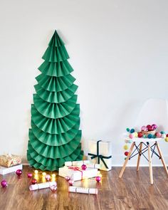 a christmas tree made out of paper sitting on top of a wooden floor next to presents