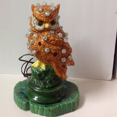 an owl figurine sitting on top of a green vase with crystal balls around it's eyes