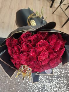 a bouquet of red roses sitting on top of a black hat and some glitters