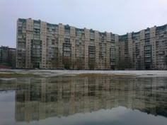 an apartment building is reflected in the water on a cold day with no one around